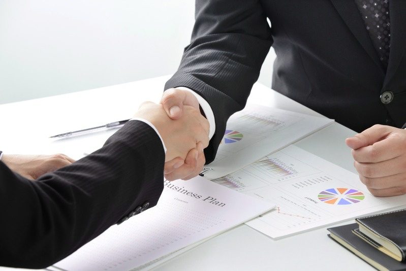 Professionals shaking hands over a business plan